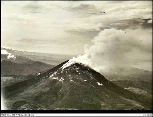 1945-01-28. Aerial view of the familiar landmark by which RAAF pilots may check their bearings is the smouldering active volcano Mount Bagana. Surrounding country is typical of the island. (Photo: Harrison, John Thomas; Australian War Memorial)